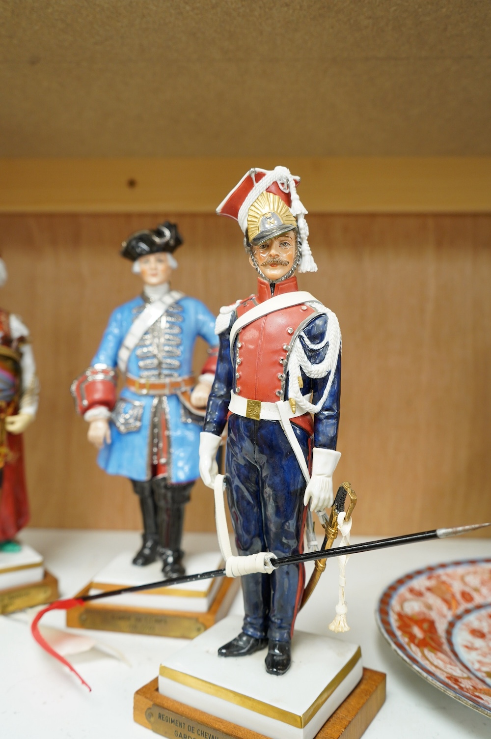 A set of four French porcelain military figures on stands to include ‘Hussards De Bercheny Officer’ and ‘Garde Du Corps’, largest 26cm high. Condition - mostly good condition with some minor losses